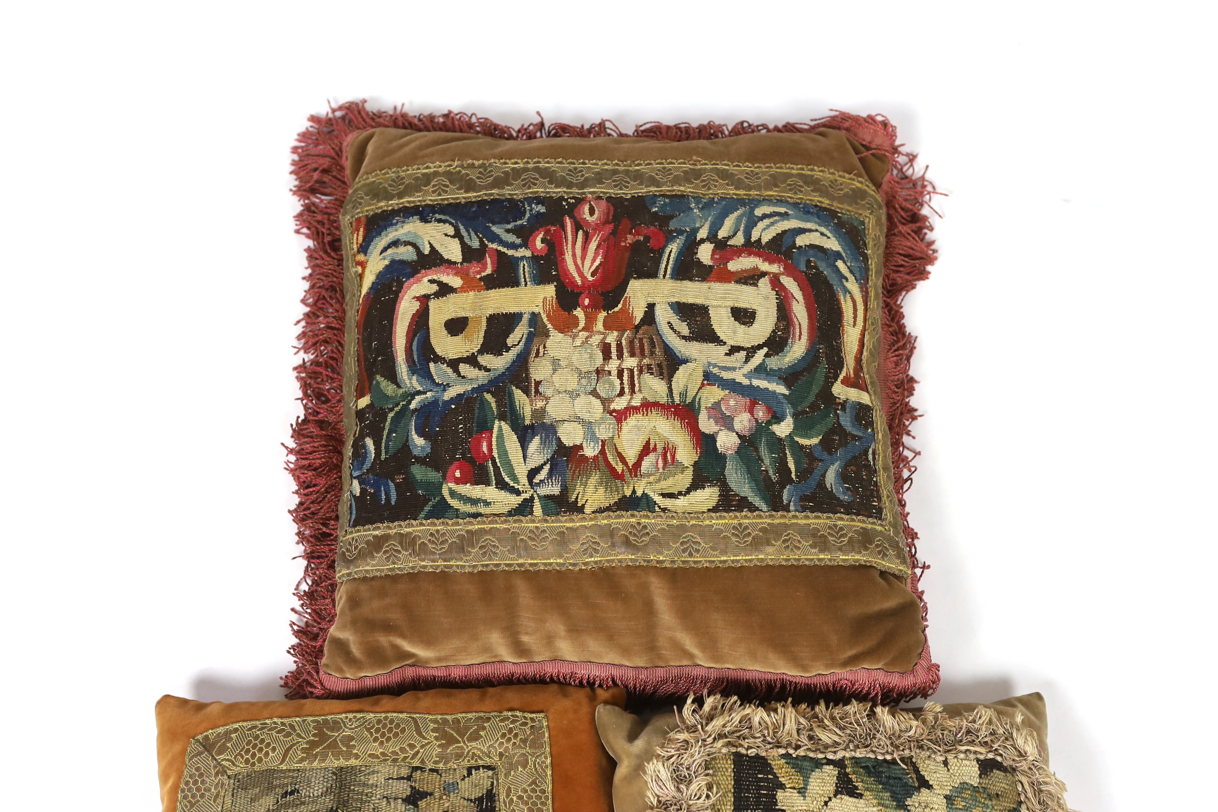 Two late 18th century Flemish verdure tapestry fragments made into cushions, plus a 19th century French Aubusson and an early 19th century Italian burgundy cut velvet damask panel, both made into cushions, all trimmed wi